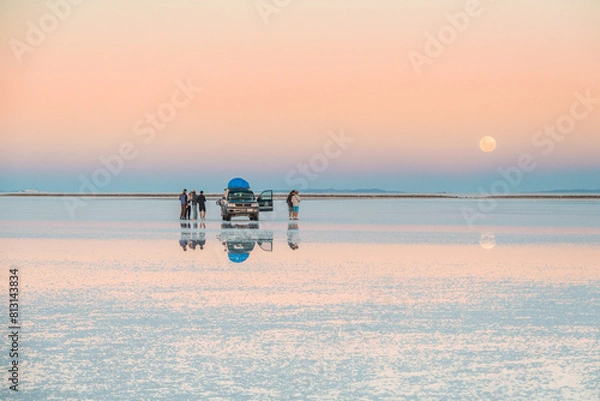 Fototapeta Reflections at Salar de Uyuni during sunset (April) - 4x4 Jeep and tourists behind mountain and mirror lake