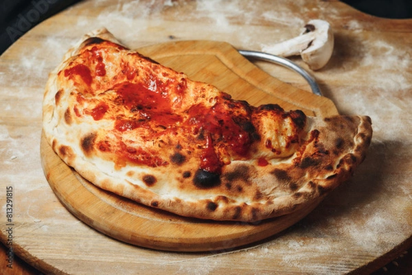 Fototapeta Rustic Calzone on a Wooden Board