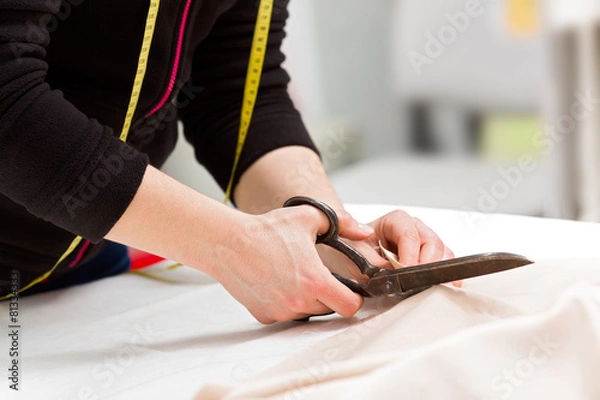 Obraz Dressmaker cutting fabric with scissors