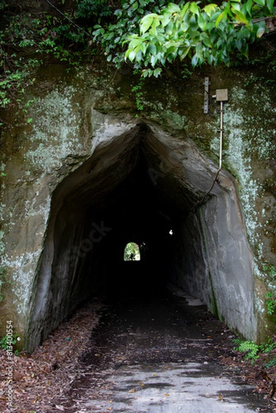 Fototapeta 人工的且つ神秘的な暗い手掘りトンネルの入り口と出口に見える人影