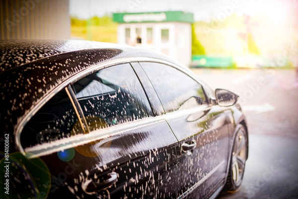 Obraz White foam is applied to the car body at the car wash