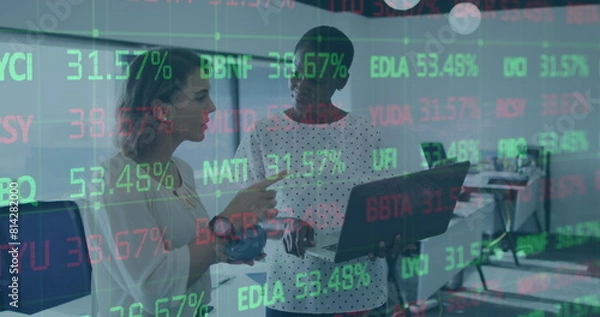 Fototapeta Image of trading board over diverse female coworkers standing and discussing reports on laptop
