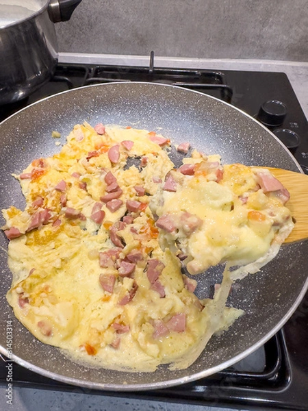 Obraz cooking egg with sausages turn over with a spatula in frying pan on stove.