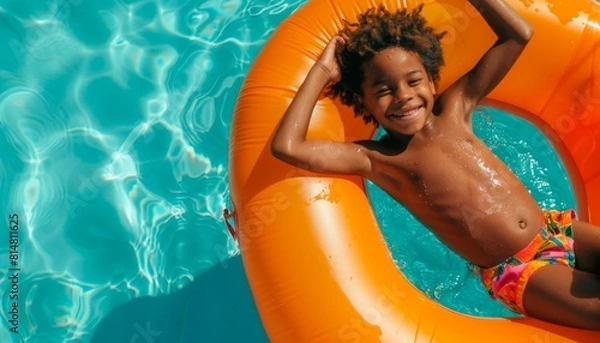 Fototapeta Smiling Black Boy on Orange Float in Pool