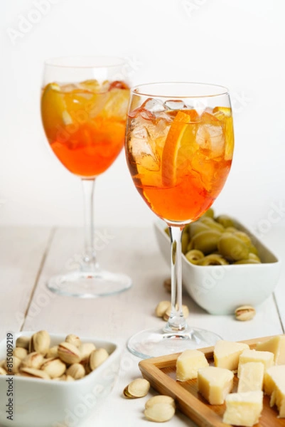 Fototapeta Happy hour with Aperol Spritz served with an orange slice in wine glasses. White wooden table, high key, high resolution