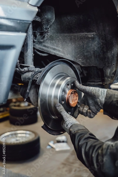 Obraz The rim is removed showing the rotor and caliper. Disc brake on car in process of new tire replacement