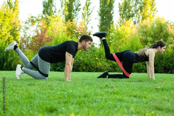 Obraz pareja de hombre y mujer haciendo deporte en el parque con bandas elásticas en las piernas. Deporte al aire libre. Estilo de vida saludable