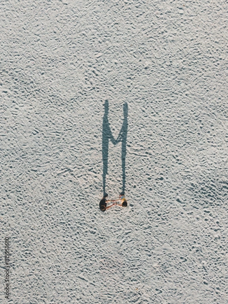 Fototapeta A lovely couple holding hands creates a heart-shaped shadow, captured from a top-down drone view.