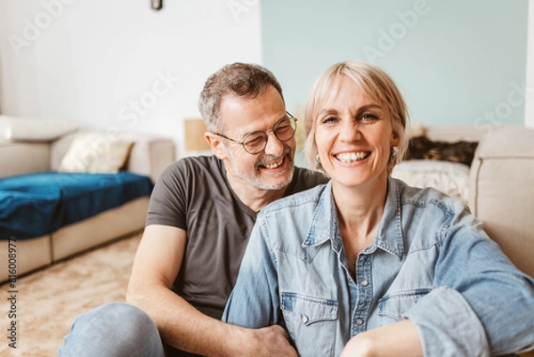 Obraz Joyful middle-aged couple laughing and smiling, enjoying quality time together at home, showcasing love and happiness.