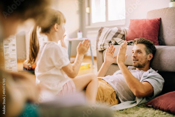 Fototapeta Father playing with daughter at home and clapping hands