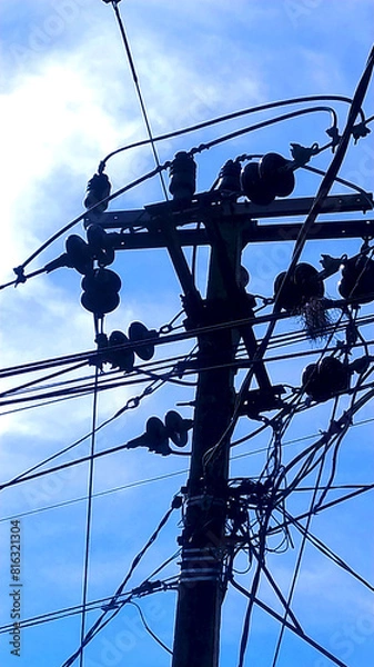 Obraz random Messy electrical cables and wires on electric pole on sky background.
