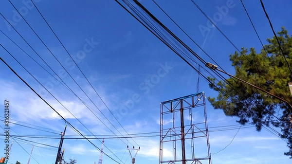 Obraz random Messy electrical cables and wires on electric pole on sky background.
