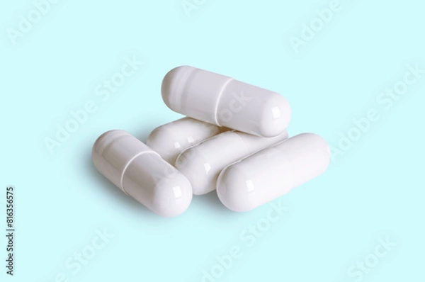 Obraz Group of white capsule pills on light blue background.