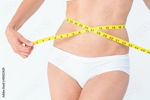 Fototapeta Attractive woman measuring her belly