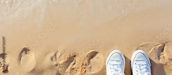 Fototapeta A summer themed selfie of fashionable white sneakers on a sandy beach captured from a top down perspective with additional space for images or text