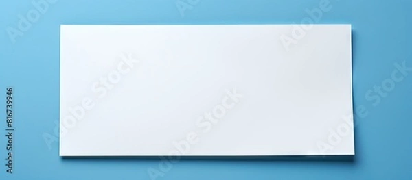 Fototapeta The image shows a blank note paper from a top down perspective on a blue background with plenty of copy space