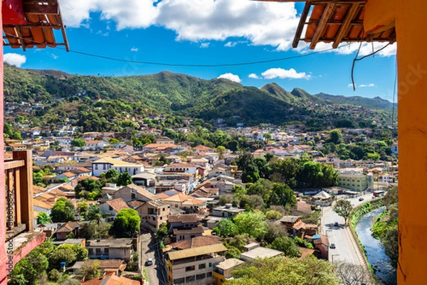 Fototapeta Partial view of the city of Sabará, Brazil. Streets, bridge, mountain, trees and blue sky with clouds.