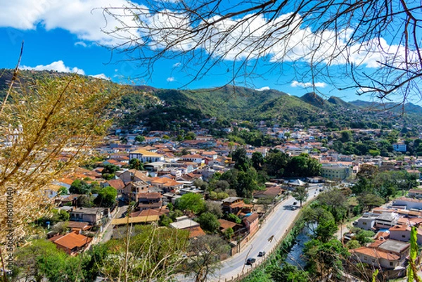 Fototapeta Partial view of the city of Sabará, Brazil. Streets, bridge, mountain, trees and blue sky with clouds.