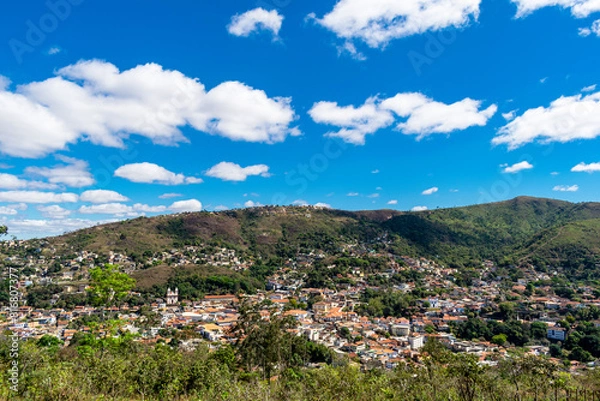 Fototapeta Partial view of the city of Sabará, Brazil. Streets, bridge, mountain, trees and blue sky with clouds.