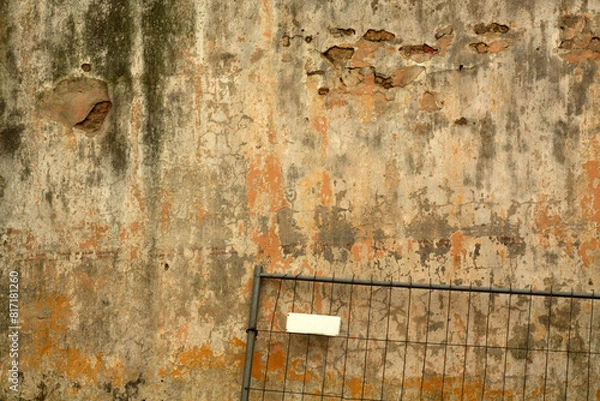Obraz Grungy metal fence against dirty weathered cement wall.