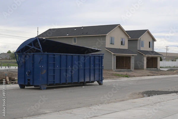 Obraz Large blue construction dumpster in front of new duplex homes under construction.