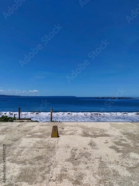 Fototapeta Scenic Ocean View from a Concrete Roadside in a Tropical Area on a Sunny, Clear Blue Sky Day