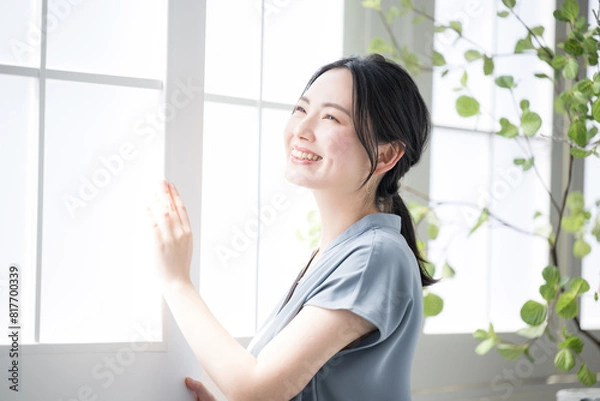Fototapeta Woman standing at window looking up toward the outside Image of relaxing and waking up early in the morning sun Short sleeves in spring and summer