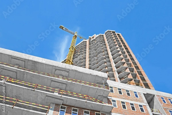 Fototapeta Crane and building construction site against blue sky
