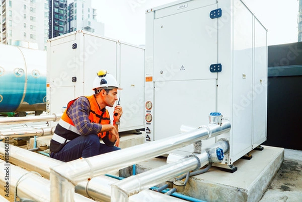 Fototapeta HAVC refrigeration system mechanic daily inspection refrigeration equipment on the roof building checking pressure and electrical control systems using radio communications to report technician team.