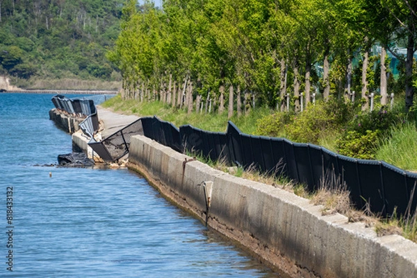 Obraz 災害でフェンスが大きくゆがんだ海沿いの遊歩道