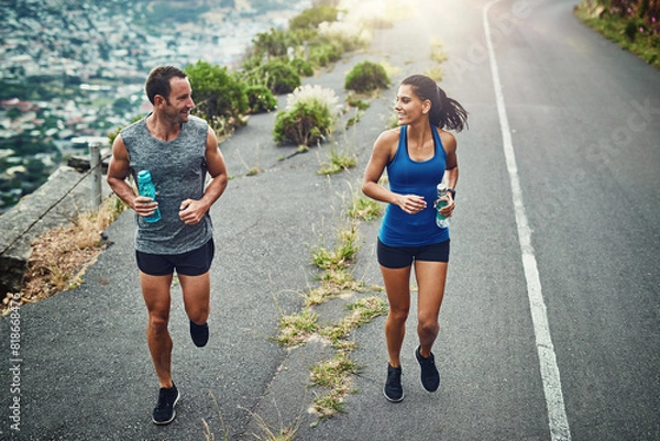 Fototapeta Fitness, running and couple with smile, routine and bottle for hydration with water and outdoor. Road, exercise and people in morning, sportswear and training together, energy and workout for race