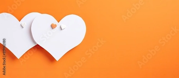 Fototapeta Minimalistic love concept depicted in a top view of a white frame constructed with two paper hearts on an orange background creating a peaceful ambiance with copy space image