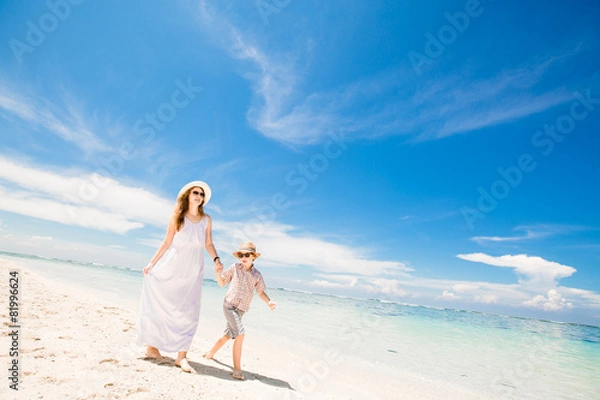Fototapeta Happy beautiful young mother and son enjoying beach time with