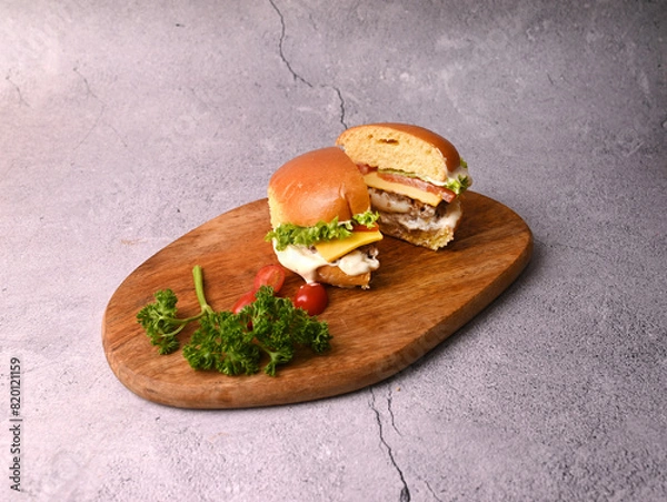 Fototapeta Half cut Beef patty burger with on a wooden plate