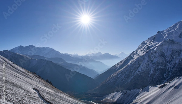 Fototapeta Sunrise seen on the way from Tilicho Base Camp to Tilicho Lake. Most popular hiking trail in Annapurna Conservation Area. Mountain chains and Manaslu summit in background. Rays radiating from the sun.