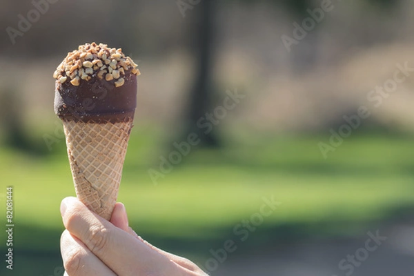 Fototapeta Ice Cream with chocolate frosting  in hand