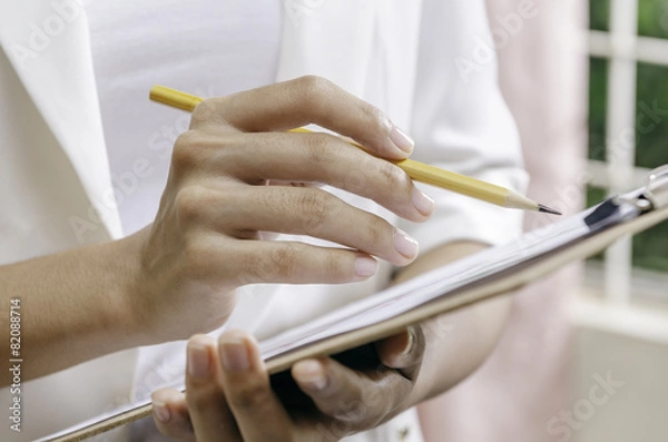 Fototapeta woman’s hands holding a binder while noting