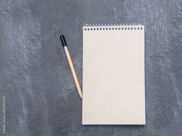 Fototapeta Top view of a open notebook with recycled paper with pencil on a slate background, school notebooks with a spiral spring, office notepad flat lay