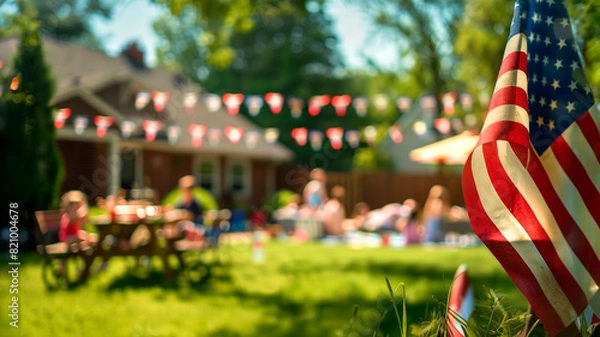 Fototapeta American flag on a patio full of guests enjoying a Memorial Day barbecue, children playing in the background. American family and friends celebrating the 4th of July, Independence Day. Copy space.
