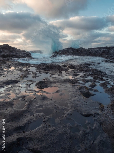 Fototapeta Vertical photo of a wave breaking in the background and small pools of water in the foreground