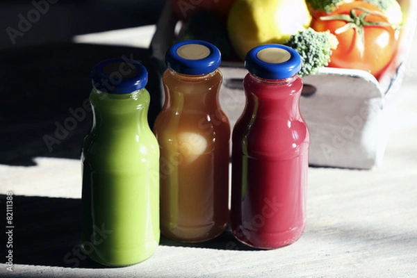 Fototapeta Bottles of juice with fruits and vegetables on table close up