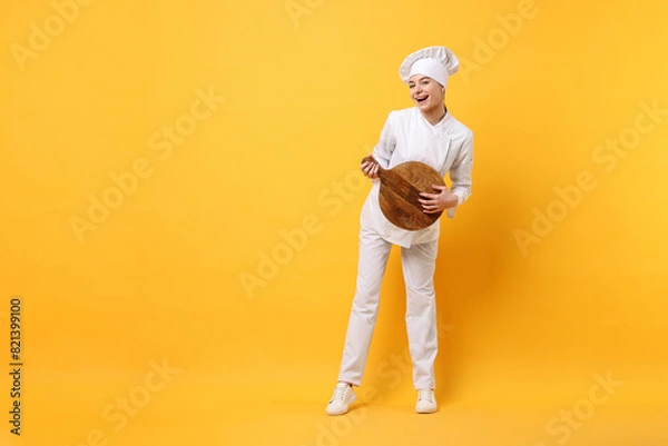 Fototapeta Professional chef with serving board having fun on yellow background. Space for text