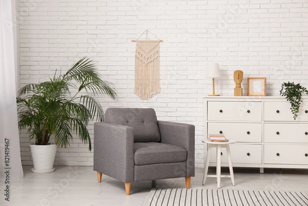 Fototapeta Armchair with chest of drawers and coffee table with book in living room