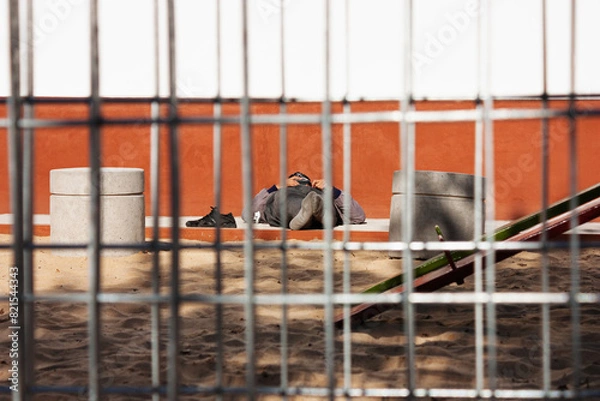Fototapeta Workerman relaxing lying down the sunlight on a playing park in his break time