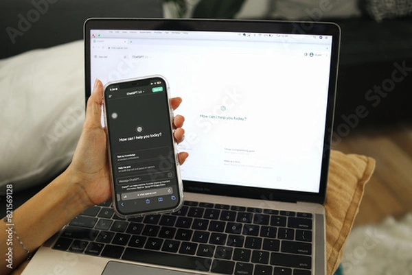 Fototapeta Application Of ChatGPT. Hand Using Smartphone And Laptop Display Chat Bot Screen