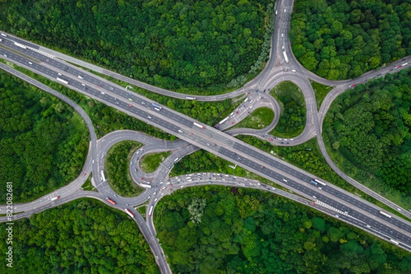 Fototapeta Aerial view above a complex motorway junction cutting through green forest