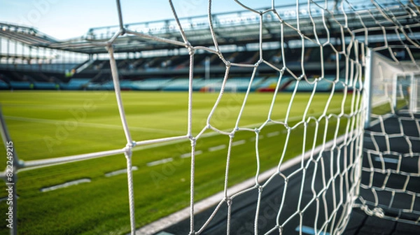 Fototapeta An empty football stadium with the focus on the meticulously maintained goal area, the net perfectly hung and the lines freshly painted, extensive copy space in the background stands.