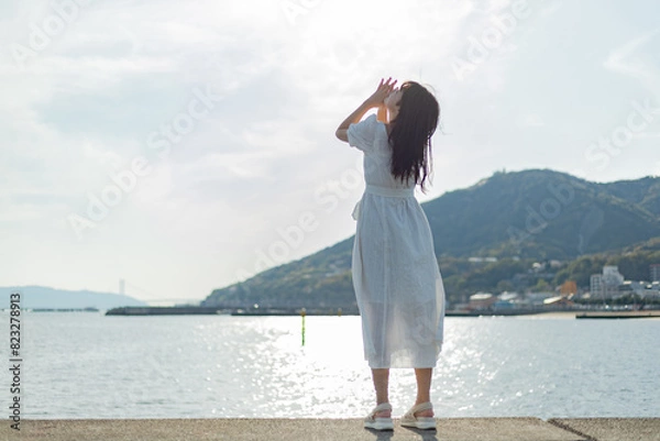 Fototapeta 海ではしゃいでいる白いワンピースの女性