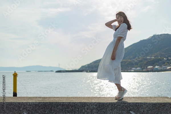 Fototapeta 海ではしゃいでいる白いワンピースの女性