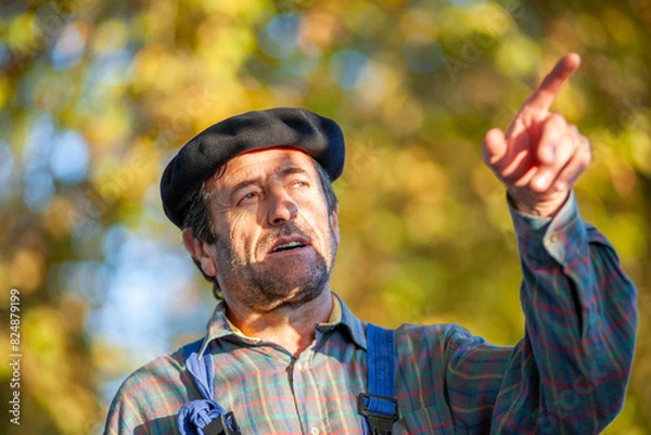 Fototapeta Portrait of a Frenchman, wearing a beret and blue dungarees smiling and gesticulating to camera